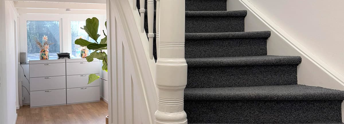 Treppenhaus mit weißem Geländer und grauem Teppich