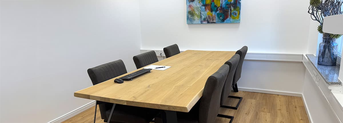 Besprechungsraum mit Holztisch und farbigem Gemälde